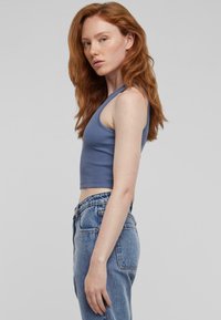 Svijetloplava rebrasta kratka majica s širokim naramenicama, uparenja s visokim strukom izblijedjelim trapericama. Glatka tkanina, ležeran kroj.