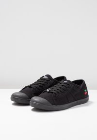 Scarpe da tennis nere in tela con punta arrotondata, tomaia texturizzata e suole in gomma nera. Presentano un piccolo logo a ciliegia multicolore sul lato.