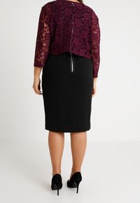 Bordó krajkový krátký kabátek s tříčtvrtečními rukávy v kombinaci s úzkou černou sukní se zadním rozparkem a černými vysokými podpatky.