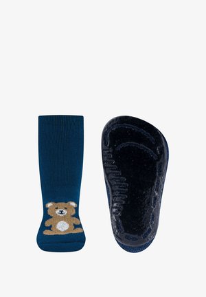 Marineblaue Socken mit einem braunen Bärenmotiv am Knöchel. Die Sohle hat eine strukturierte, rutschfeste Oberfläche. Weicher Strickstoff.