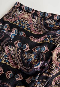 Černá tkanina s paisley vzorem v růžové, modré a zlaté barvě. Obsahuje květinové akcenty a zmačkanou texturu, která ukazuje složité detaily designu.