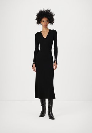 Black ribbed knit long-sleeve dress with a V-neckline and fitted silhouette. Features unique silver hardware accents at the sleeve cuffs.