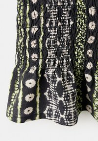 Tissu noir avec des fronces élastiques, décoré de motifs floraux crème et de rayures verticales abstraites vertes.