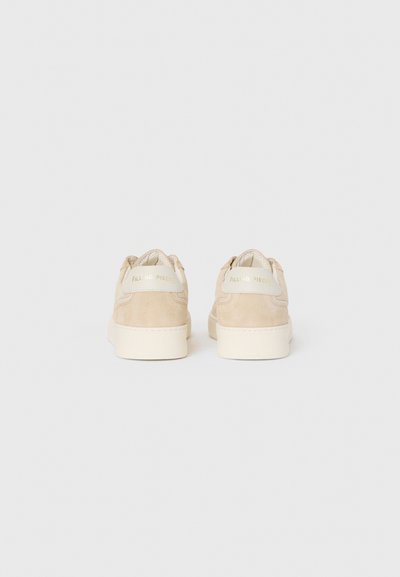 Beez suedesneakerid vaadates tagant, valgete talladega ja "FILLING PIECES" brändimisega kontsatelgedel.