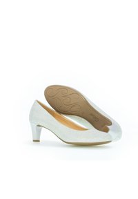 Scarpe con tacco in tessuto argento chiaro con finitura liscia. Presentano una punta rotonda e un tacco argentato metallico. Suola texturizzata color nocciola.