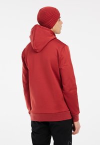 Rode hoodie met een gladde textuur, aansluitende manchetten en zoom. Draag het met een bijpassende geribbelde gebreide muts, met een ronde kroon.
