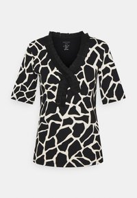 Korte mouwen zwart en crèmekleurig top met een giraffeprint, V-halslijn met ruches, en een fitted silhouet.