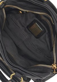 Interno di una borsa in pelle nera con zip dorata, fodera in tessuto, più scomparti e un'etichetta del brand. Texture liscia, design pratico.