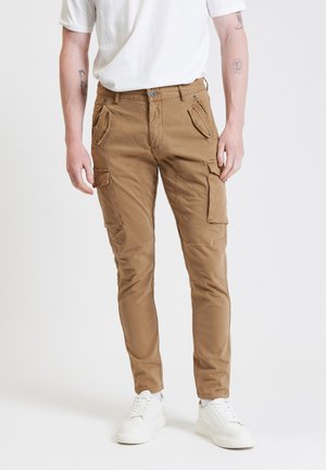 Khaki cargobroek met meerdere zijzakken, slim fit ontwerp, katoenen stof en zilverkleurige hardware; gecombineerd met witte sneakers.