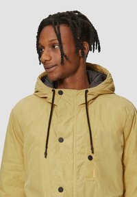 Geel hoodiejack met zwarte trekkoorden, drukknoopsluiting en een voorkantzak. Geweven stof met een gladde binnenvoering.
