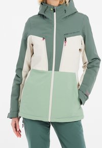 Veste résistante aux intempéries de couleur verte et crème avec capuche, dotée de poches zippées, de panneaux contrastants et d'une coupe décontractée.