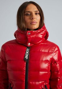 Rode gewatteerde jas met hoge kraag, glanzende textuur, zwarte rits en merklabel op de voorkant. Heeft een slim fit ontwerp en zijzakken.