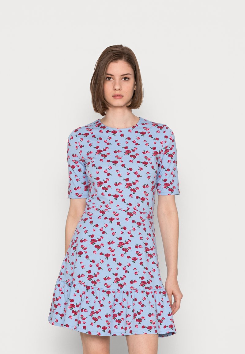 Vestido azul claro com mangas curtas, apresentando um padrão floral de rosas vermelhas. Possui uma bainha em camadas com babados e um corpete ajustado.