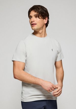 T-shirt a maniche corte di colore grigio chiaro realizzato in tessuto morbido, con un piccolo logo ricamato a sinistra sul petto, scollatura tonda e vestibilità standard.