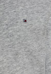 Gray cotton t-shirt with a soft texture, featuring a small embroidered logo in navy, red, and white on the left chest.