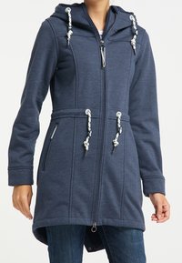 Navy blue long coat in soft, textured fabric with a hood, adjustable drawstrings, zip closure, and side pockets.