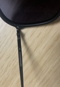 Černé sluneční brýle s tmavými čočkami. Rám má matný povrch a na ramene má vyryté značky. Textura je hladká.
