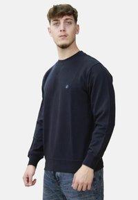 Felpa blu navy in morbido tessuto con scollatura rotonda, polsini e orlo a coste. Presenta un piccolo logo sul petto.