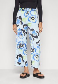 Light blue floral pants featuring large black, blue, and green flower patterns, with an elastic waistband and wide-leg design.