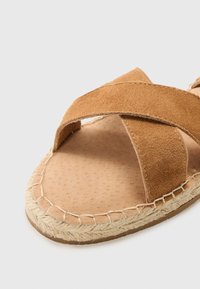 Brune semsket sandaler med kryssede stropper, naturlig skinnsåle og vevd jute-mellomsåle. Glatt tekstur med synlige sting.