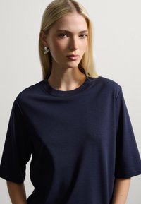 Navyblauwe korte mouwen T-shirt van zachte stof met een ronde halslijn. Glad materiaal en een comfortabele pasvorm, voorzien van subtiele stikseldetails.