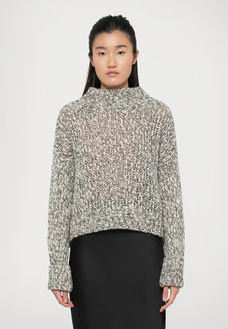 Chunky striktrøje i sort og hvid med høj hals, lange ærmer og ribbede manchetter. Tekstureret design med cropped pasform.