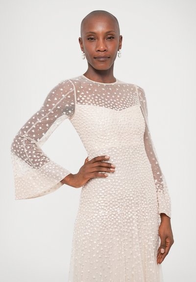 Haljina dugih rukava s prozirnim, točkicama ukrašenim gornjim dijelom, prilagođenim strukom i raširenim rukavima; izrađena od laganog materijala u svijetloplatoj boji.