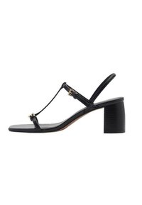 Sandal con tacco nero con design a T-strap, cinturini testurizzati e tacco a blocco. Presenta dettagli in metallo dorato e una suola liscia.