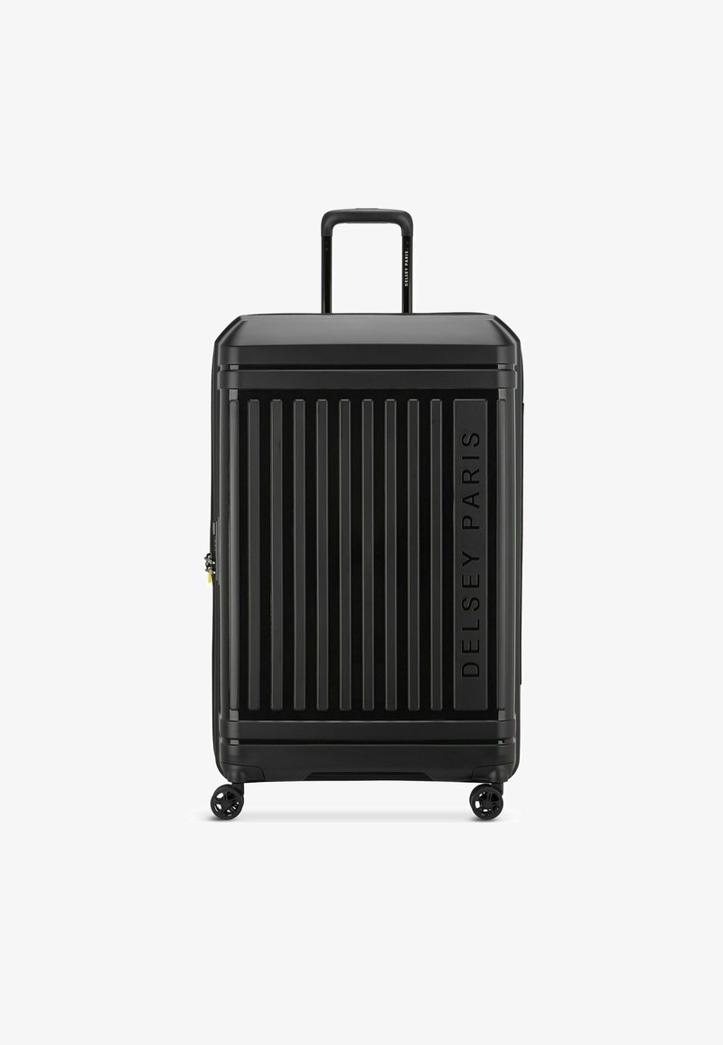 Valigia rigida nera con scanalature verticali, dotata di manico retrattile e quattro ruote per una facile mobilità. Logo "Delsey Paris" impresso.