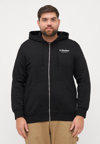 Zwarte zip-up hoodie met kangoeroezakken, capuchon met trekkoord en witte "JJ Studios" logo op de borst. Getextureerde stof met ribbels aan de manchetten.