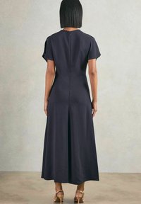 Marineblaues Kleid mit lockerer Passform, kurzen Ärmeln, Schlitz im Rücken und einem Reißverschluss am Hals, aus glattem Stoff gefertigt. Glatte Textur, bodenlang.