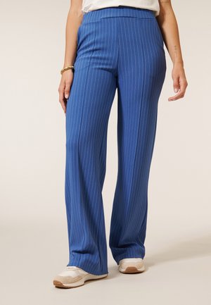 Blauwe gestreepte wijde beenbroek van een gladde stof, met een hoge taille en subtiele verticale lijnen, gecombineerd met witte sneakers.