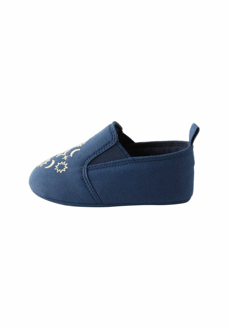 Pantoufle en tissu bleu marine avec une coupe basse et des panneaux latéraux élastiques. Présente une broderie en forme de croissant de lune et d'étoiles de couleur crème à l'avant.