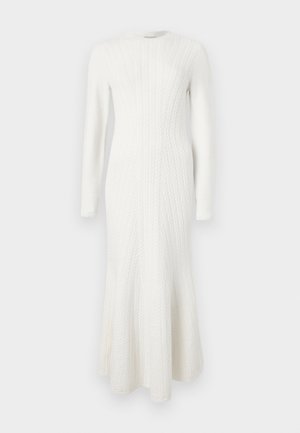 Weißes gestricktes Kleid mit langen Ärmeln, das ein Zopfmuster und einen ausgestellten Saum aufweist. Sanfte Textur und figurbetonte Silhouette.