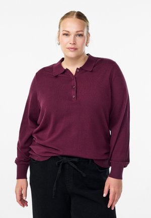 Polo shirt bordeaux à manches longues avec patte de boutonnage et poignets côtelés, associé à un pantalon noir ample avec taille élastique.