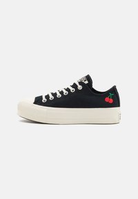 Sneakers neri a bassa altezza con suola in gomma bianca, caratterizzati da ciliegie rosse ricamate sul lato esterno e un sistema di allacciatura con occhielli standard.