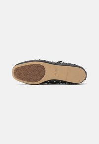 Black rubber shoe sole with a textured tan inlay. Features silver studs along the edges and a distinctive heart pattern on the surface.