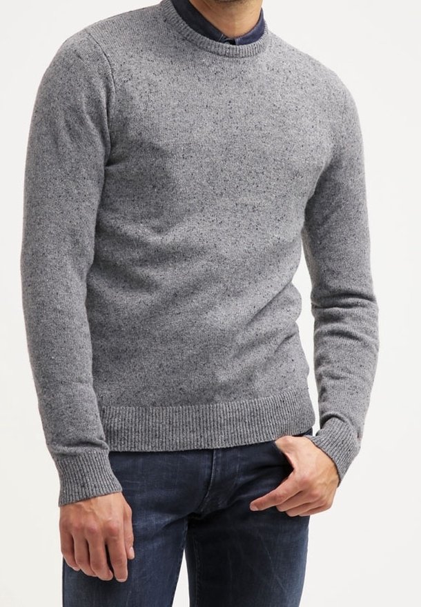 Pull gris clair en tricot avec col rond et poignets et ourlet côtelés. Texture subtilement mouchetée, porté par-dessus une chemise sombre à col.