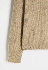 Beżowy sweter w prążki wykonany z miękkiego materiału, z długimi rękawami i luźnym krojem. Tekstura jest lekko puszysta z subtelnym połyskiem.