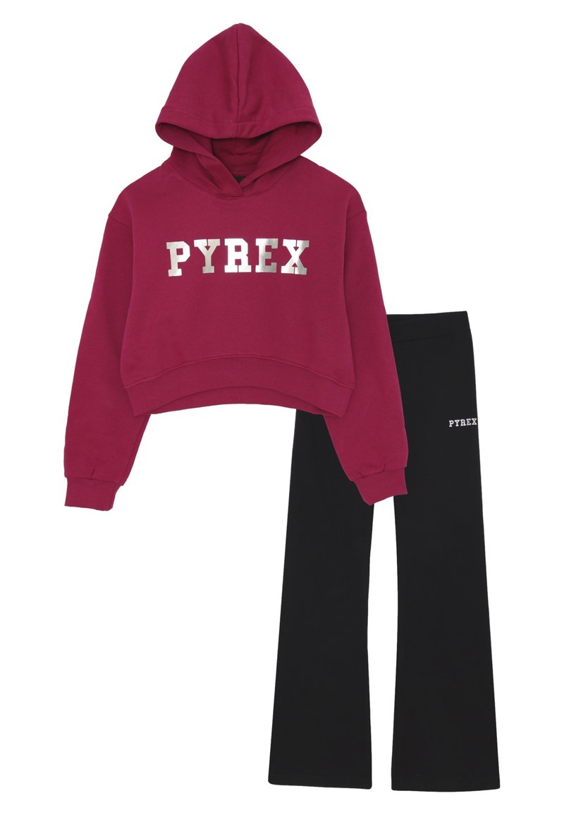 Cropped hoodie rossa con testo argento "PYREX" abbinata a pantaloni neri svasati con logo bianco "PYREX" sulla coscia.