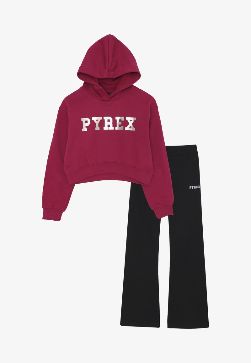 Cropped hoodie rossa con testo argento "PYREX" abbinata a pantaloni neri svasati con logo bianco "PYREX" sulla coscia.