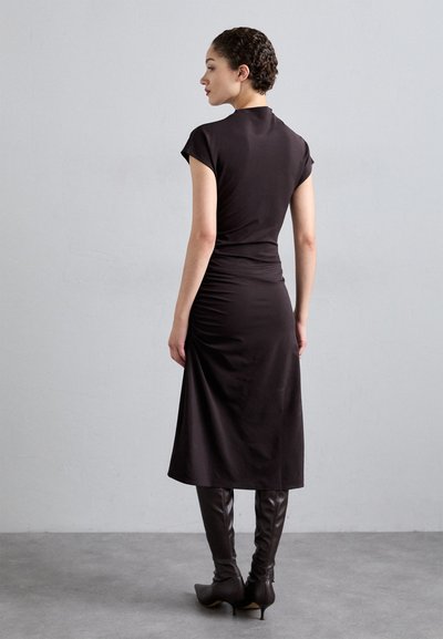 Rochie neagră, ajustată, cu mâneci scurte, textură moale și tiv până la genunchi, asortată cu bote cu toc înalt, brown, cu vârf ascuțit.