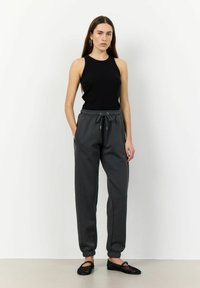 Svart ribbad linne, grå sweatpants med elastisk midja, uppvikta anklar, sidofickor och svarta flätade ballerinas.