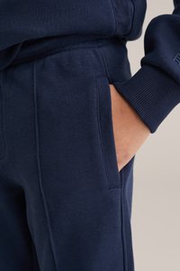 Marinblå sweatpants i bomullsblandat tyg med sidoficka, elastisk midja och ribbade muddar för en åtsittande passform.