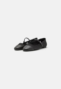 Black flat shoes made of smooth leather and mesh, featuring a rounded toe, ankle strap, and contrasting textured panels.