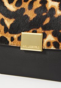 Leopard print hair-on-hide texture with a black leather base. Features a gold logo hardware accent. Compact, rectangular shape.