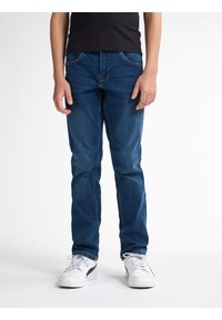 Tmavě modré džíny se slim fit, s předními kapsami, kontrastním prošíváním a klasickým designem pěti kapes. Nosené s bílými teniskami.