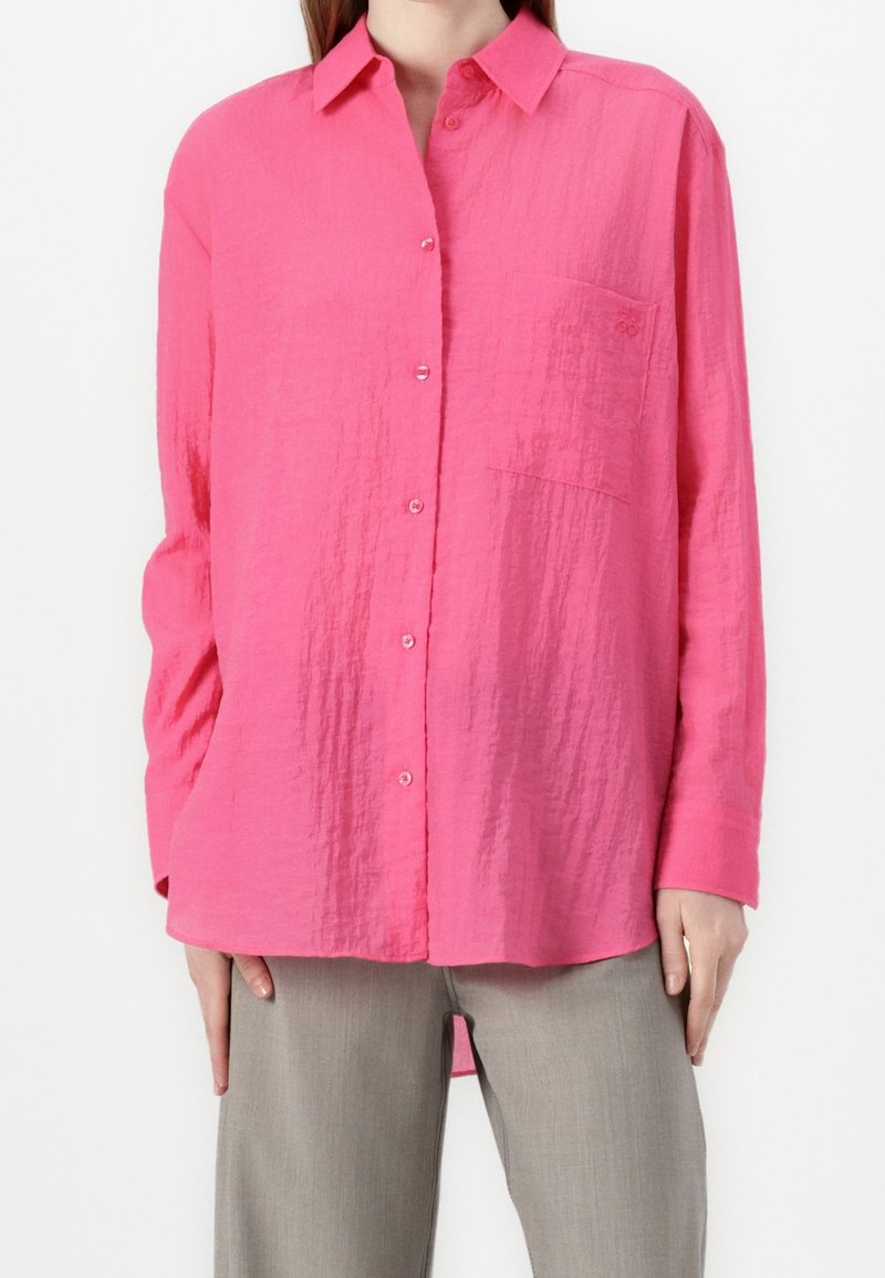 Knopf-up-Hemd in leuchtendem Pink, hergestellt aus leichtem Textilgewebe, mit Kragen, langen Ärmeln und einer Brusttasche.