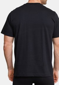 T-shirt nera in cotone, maniche corte, collo tondo, design semplice, texture liscia, con orlo dritto sul fondo e senza motivi o loghi visibili.
