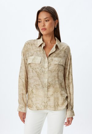 Camisa de botones de patrón mármol beige con dos bolsillos en el pecho, mangas largas y un corte relajado. Textura de tela suave y ligera.